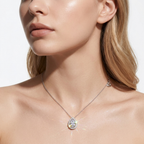 A close-up of a model wearing a delicate silver chain necklace with a teardrop-shaped clear gemstone pendant that reflects light.